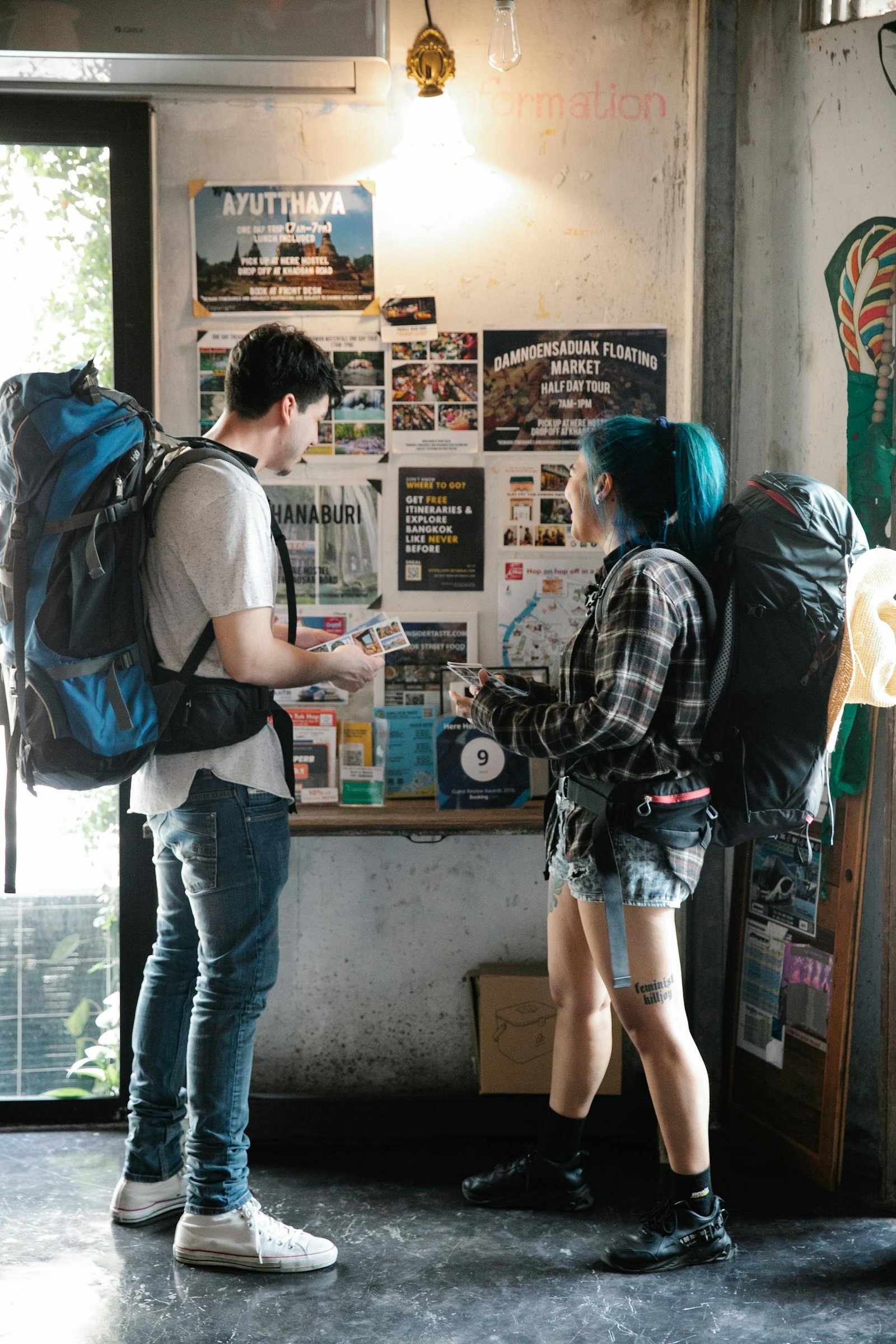 Unrecognizable couple of travellers standing near information board